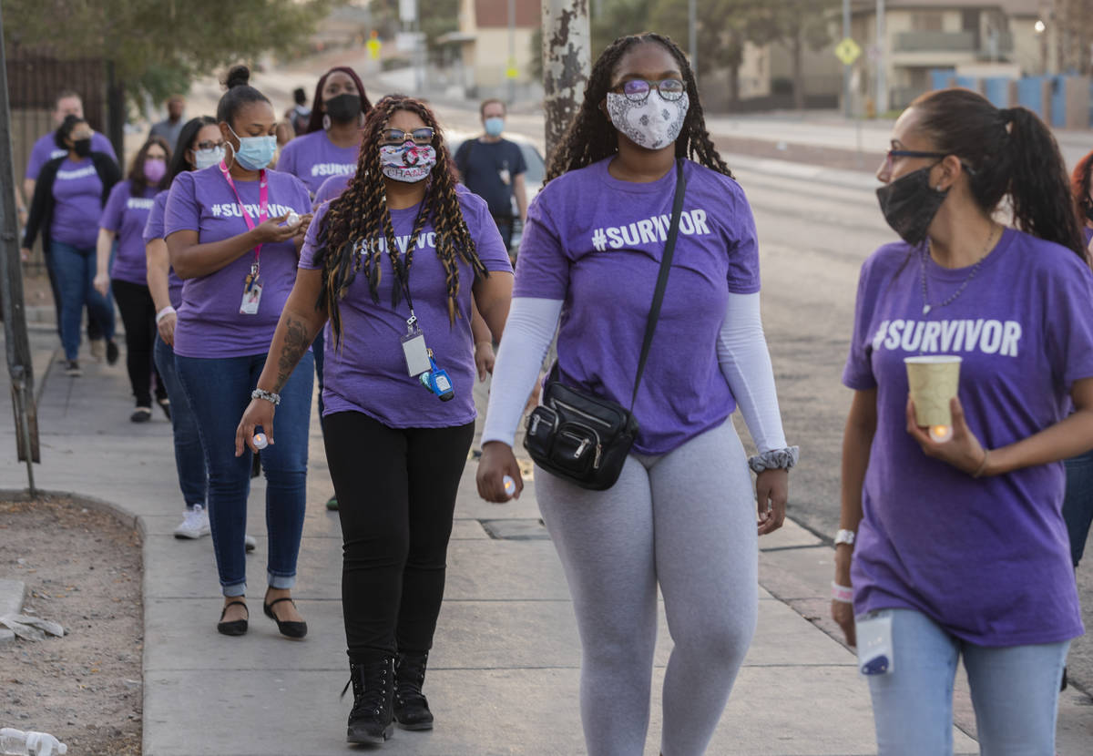 The Shade Tree staff members walk down West Owens Avenue to participate in a candlelight vigil ...