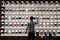 Salesperson Lucas Nascimento rearranges masks for sale at the COVID-19 Essentials store in the ...