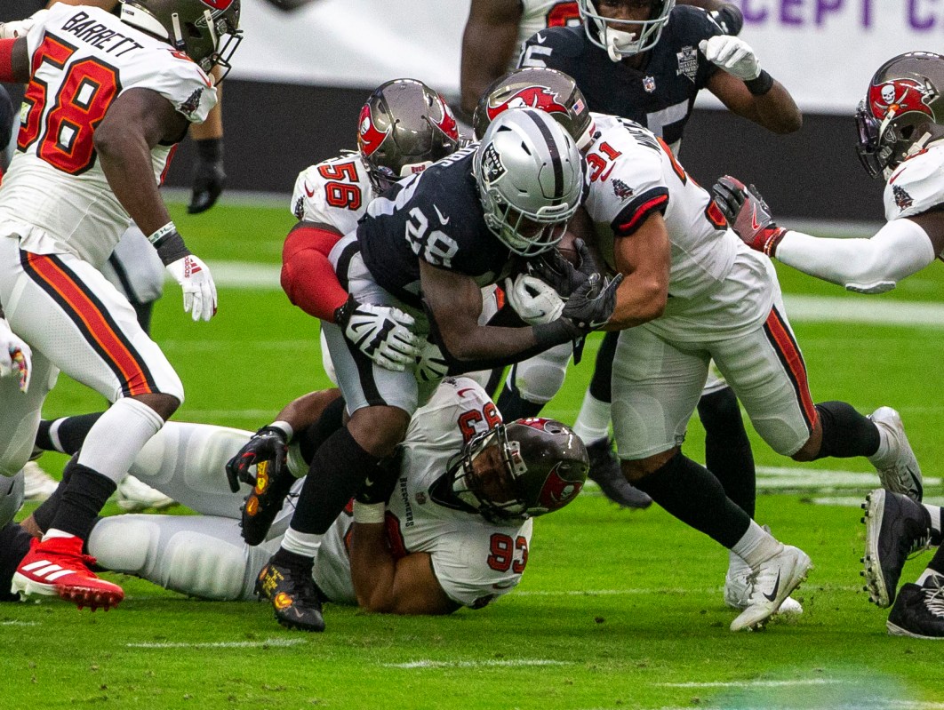 Las Vegas Raiders running back Josh Jacobs (28) is brought down by defensive end Ndamukong Suh ...