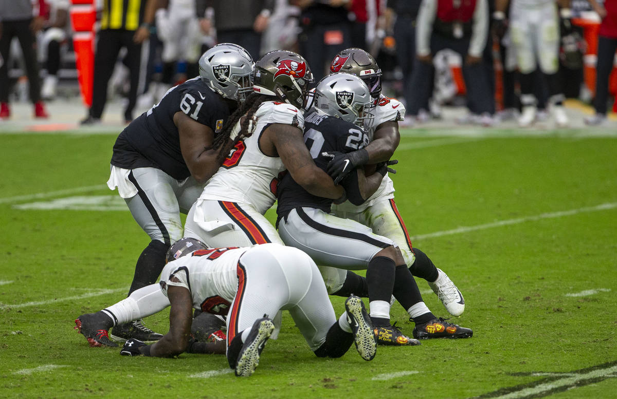 Las Vegas Raiders center Rodney Hudson (61) tries to assist as running back Josh Jacobs (28) is ...