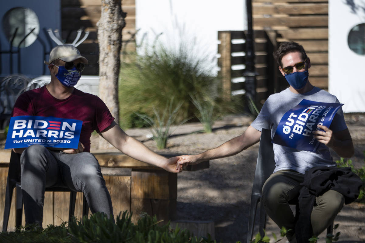 Audience members hold hands at an LBGTQ-focused campaign event for Joe Biden and Kamala Harris ...