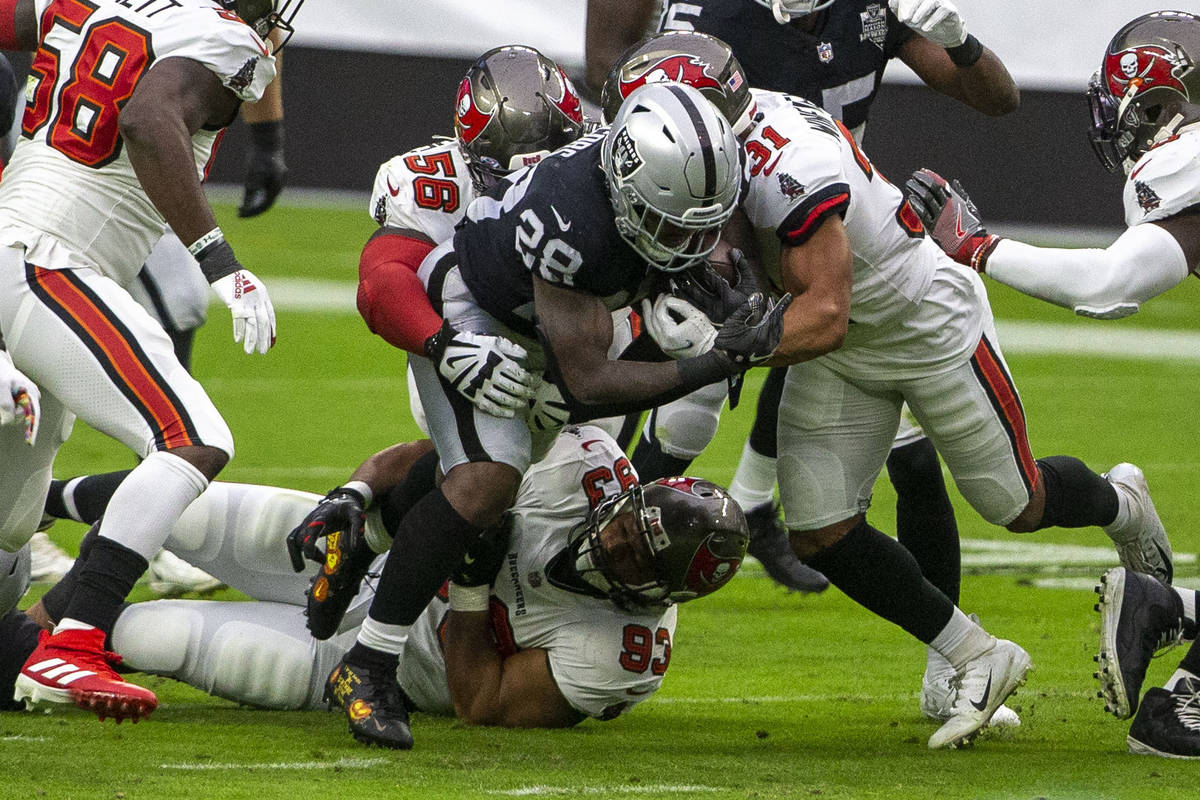 Las Vegas Raiders running back Josh Jacobs (28) is brought down by defensive end Ndamukong Suh ...