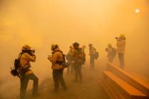 Firefighters with Cal Fire are enveloped in smoke as fire from the Green Fire passes by near ho ...
