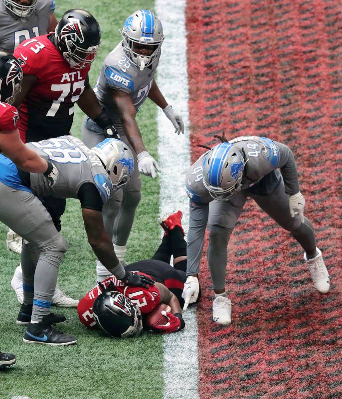 Detroit Lions players point at the football held by Atlanta Falcons' Todd Gurley during the fou ...