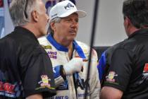 John Force talks to crew members after his Funny Car blew an engine and destroyed the body of h ...