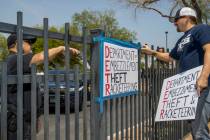 A security guard instructs Jon Berry, right, to take down a sign he attached to a fence in fron ...
