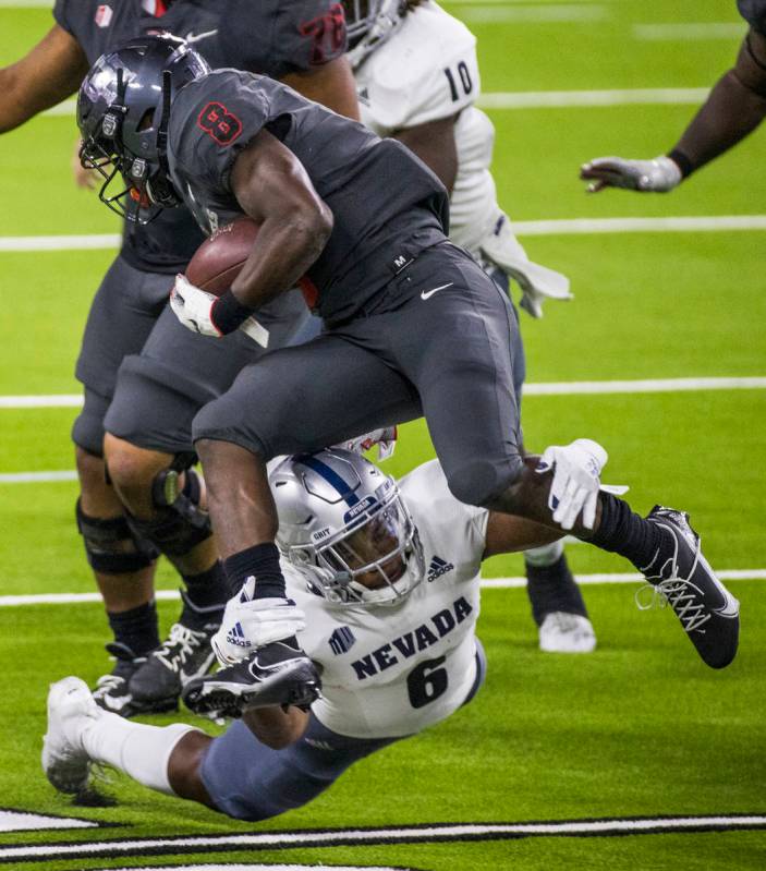 UNLV Rebels running back Charles Williams (8, top) is grabbed from below by a diving Nevada Wol ...