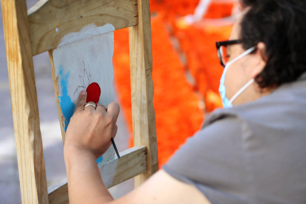 Isaias Urrabazo paints a chair which will be part of his Dia de los Muertos altar, at his home ...