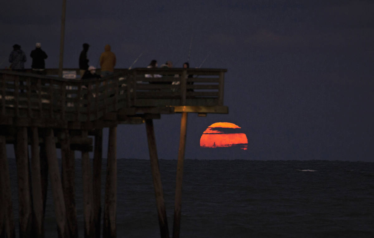 The Halloween full moon rises over the Atlantic Ocean with the Virginia Beach Fishing Pier in t ...