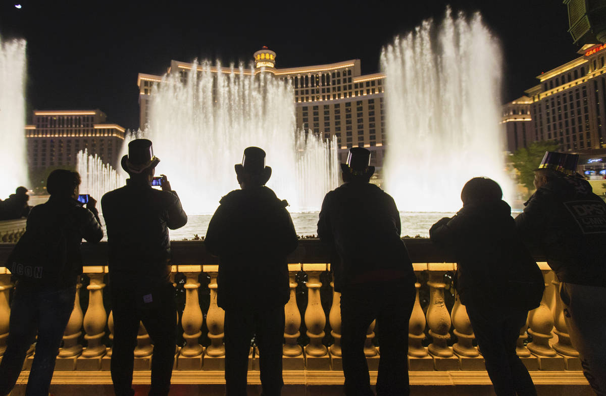 People watch the Bellagio fountain show on the Strip on New Year's Eve, Tuesday, Dec. 31, 2019, ...