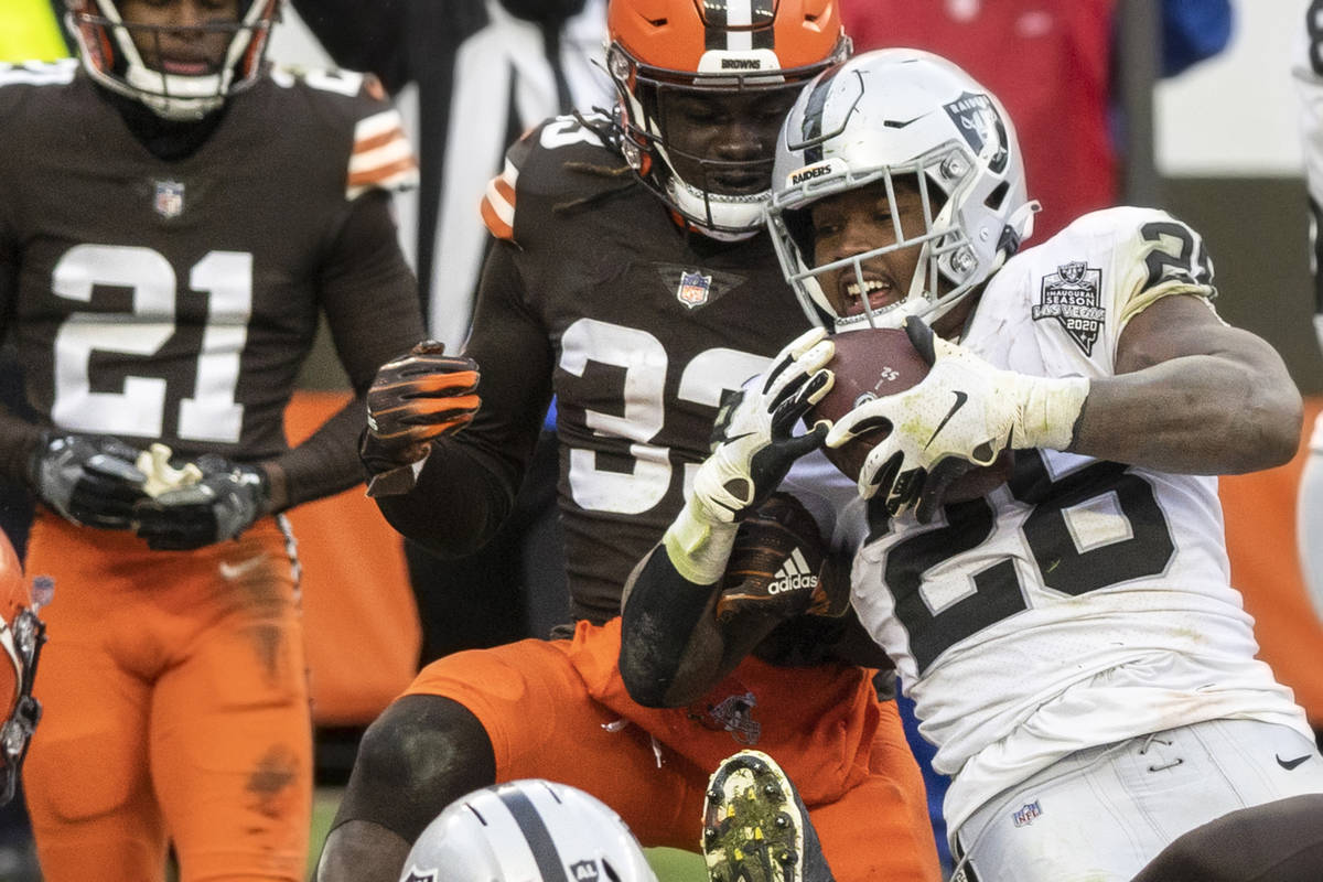 Las Vegas Raiders running back Josh Jacobs (28) fights for extra yardage with Cleveland Browns ...