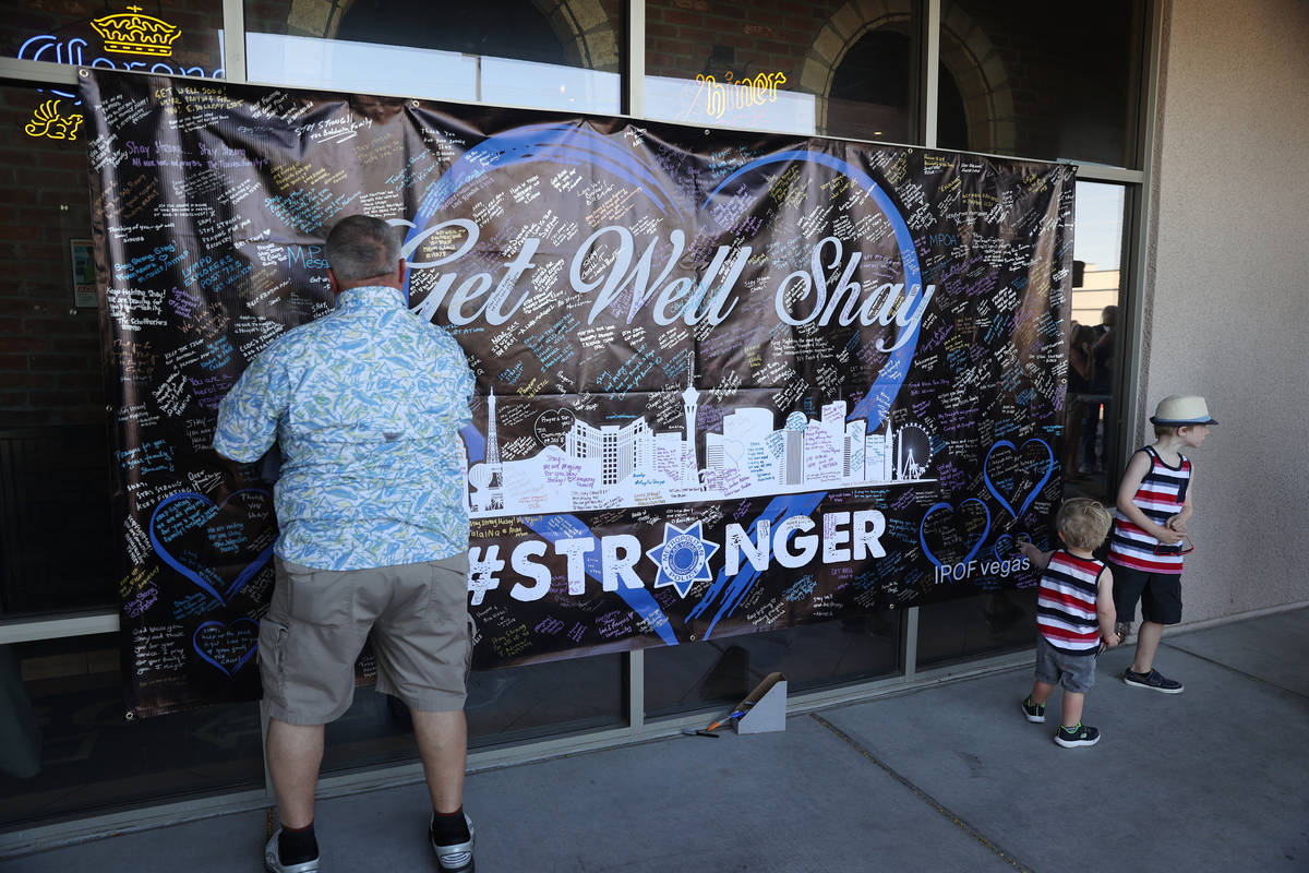 A man signs a banner in support of wounded Las Vegas police officer Shay Mikalonis at the Big B ...