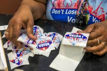 Elections worker Robin Wright readies "I Voted" stickers for mail-in ballot drop off voters dur ...