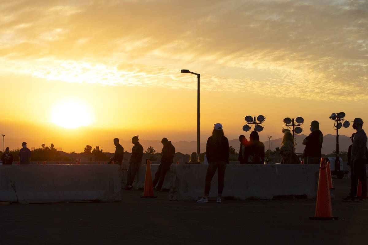 The sun rises behind voters as they wait in line nearly an hour before the voting site at Las V ...