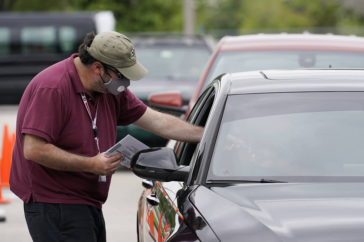 Eddy Estrada, with the Miami-Dade Elections Dept., collects a mail-in-ballot at the elections d ...