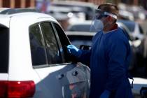 A medical worker tests a patient for COVID-19 during an event hosted by Clark County Commission ...