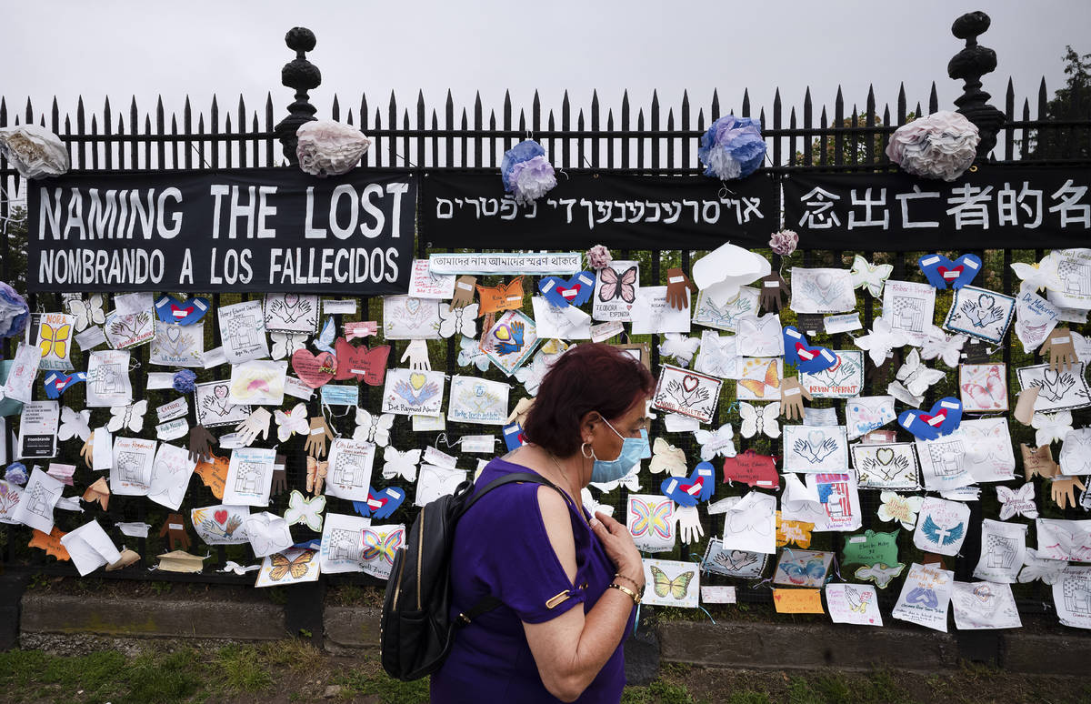 A woman passes a fence outside Brooklyn's Green-Wood Cemetery adorned with tributes to victims ...