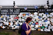 A woman passes a fence outside Brooklyn's Green-Wood Cemetery adorned with tributes to victims ...