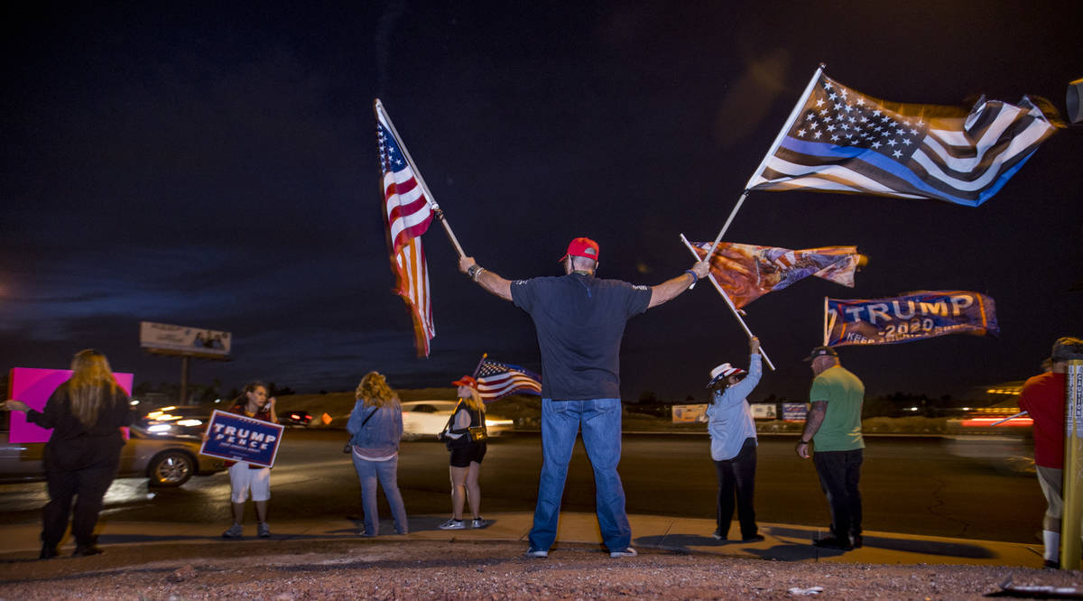 Raul Latorre waves two flags as protests continue outside the Clark County Election Department ...