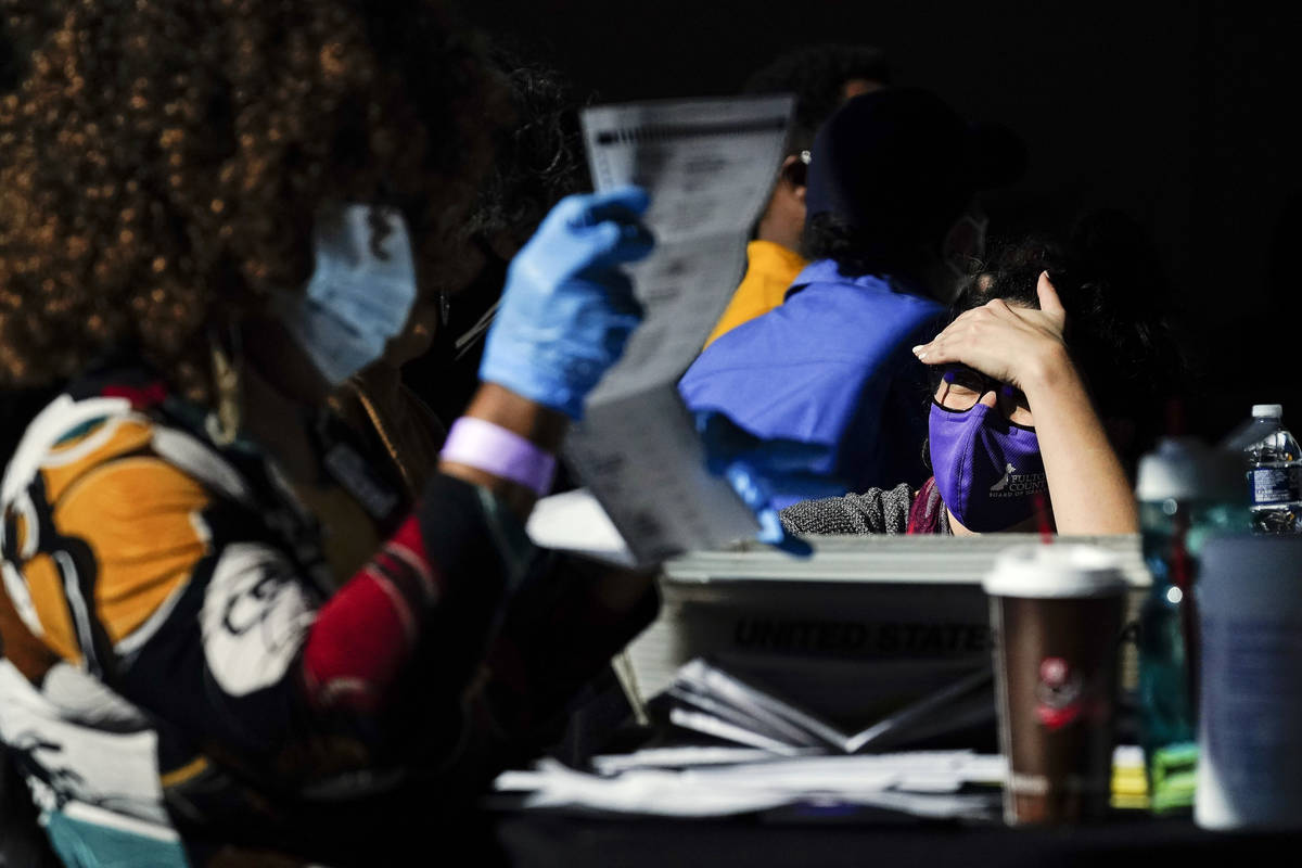 An election supervisor answer questions from an election worker as vote counting in the general ...