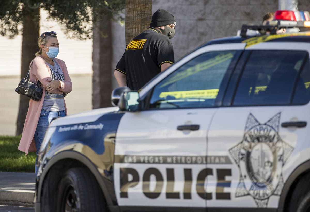 Individuals talk with Las Vegas police officers as they investigate a homicide in the central v ...