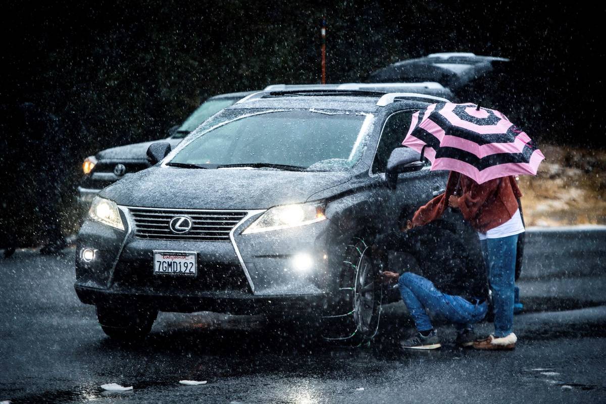 Motorists install snow chains along Highway 330 near Running Springs, Calif., as the first snow ...