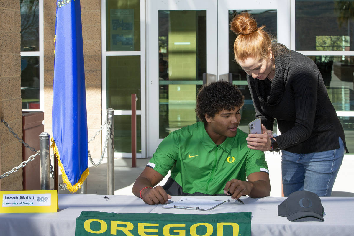 Jacob Walsh, who will play baseball for University of Oregon, looks at photos with his mother, ...