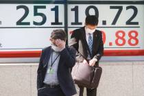 People walk by an electronic stock board of a securities firm in Tokyo, Tuesday, Nov. 10, 2020. ...