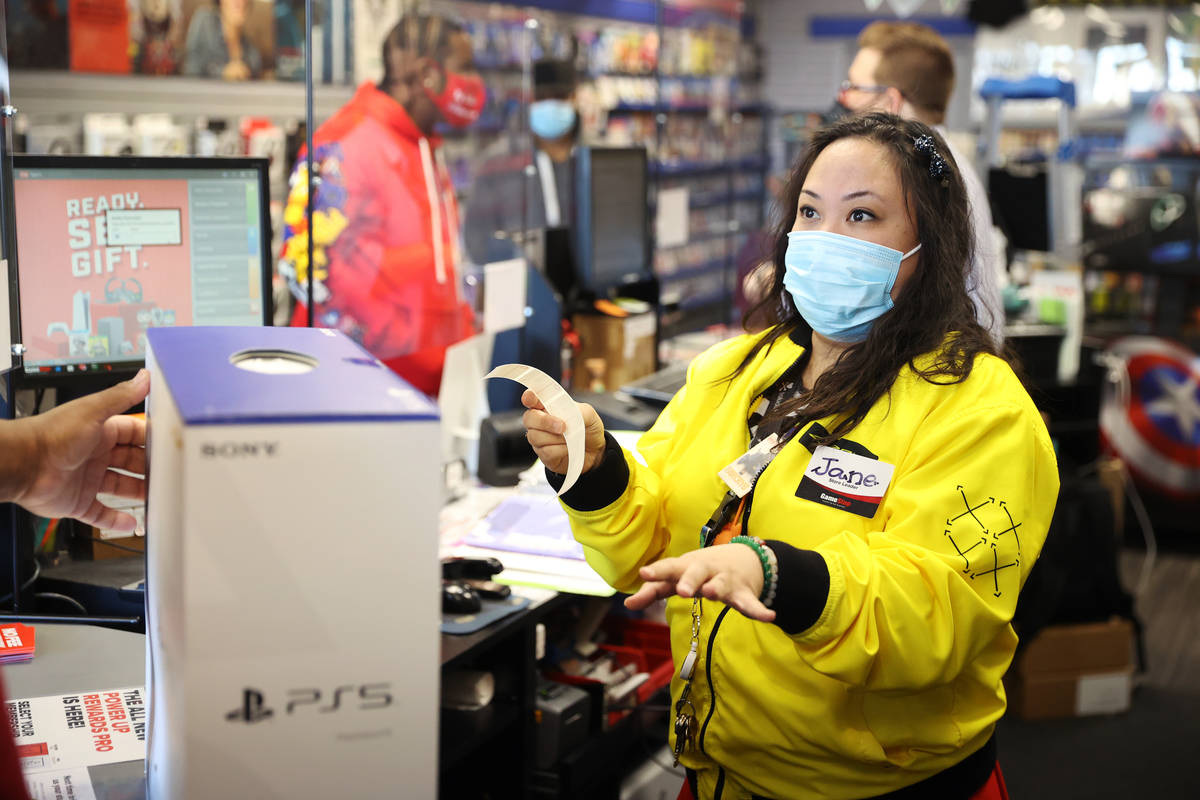 Jane Esposo gives a customer a Play Station 5 at GameStop, 9975 S Eastern Ave., in Las Vegas, T ...