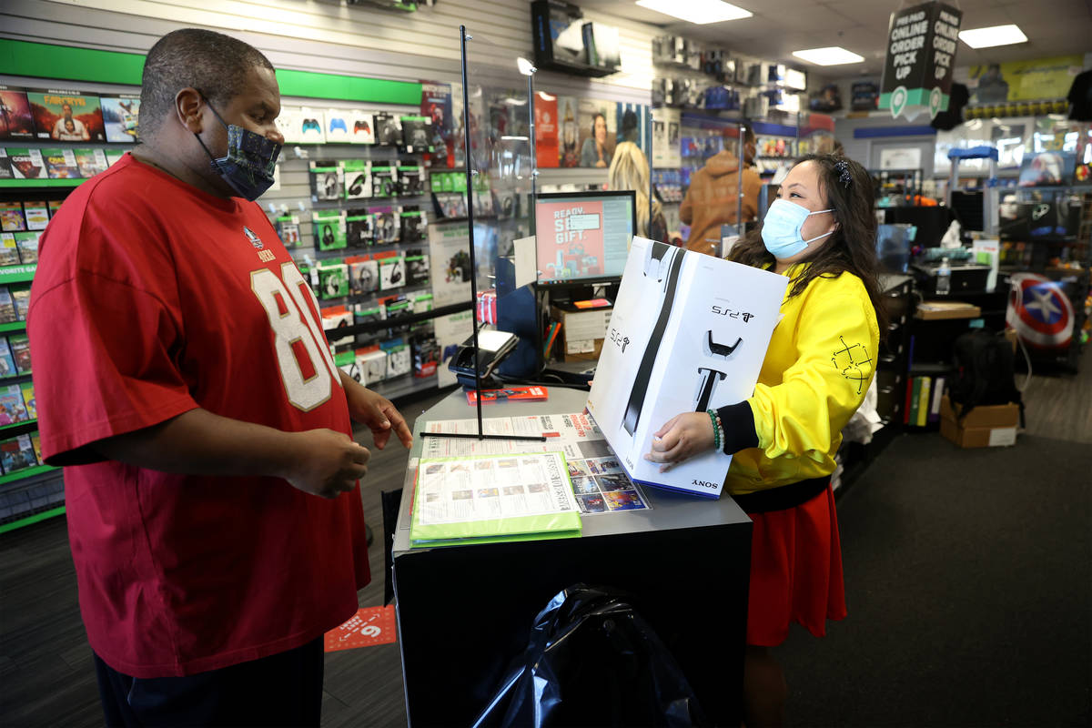 Chris Brown picks up a Play Station 5 console from store manager Jane Esposo at GameStop, 9975 ...
