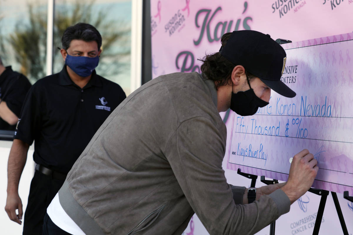 Golden Knights defenseman Shea Theodore sings a check for 50,000 dollars with Dr. Rupesh Parikh ...