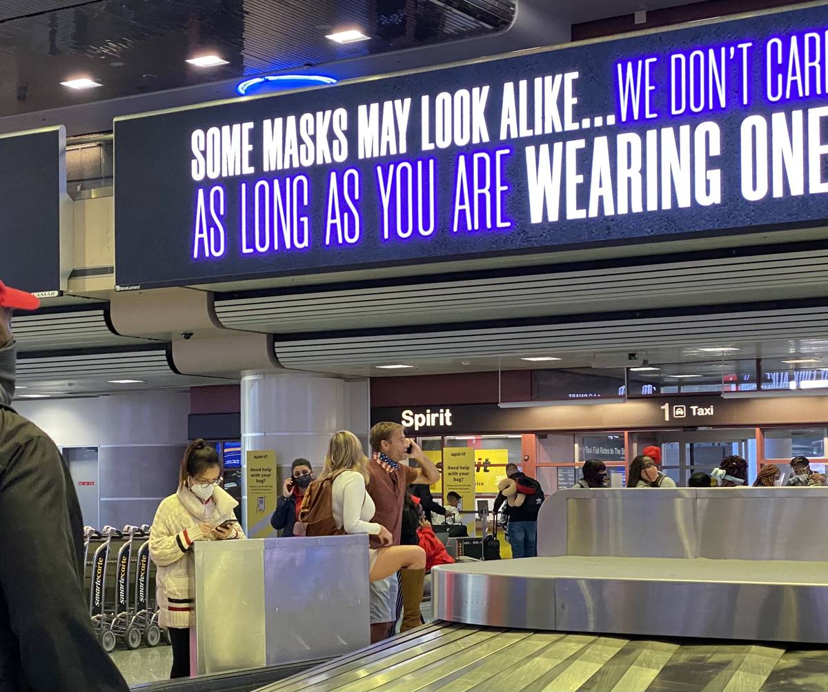 A message about wearing masks plays across a screen as a couple stand with their face coverings ...