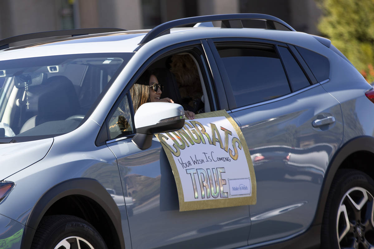 A car parade passes Las Vegan Lauren Cleveland, who received a new puppy from Make-A-Wish South ...