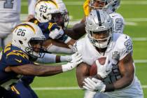 Las Vegas Raiders running back Josh Jacobs (28) breaks through the arm tackles of Los Angeles C ...