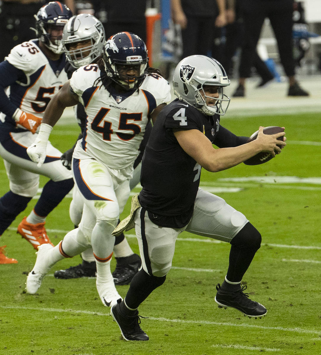 Las Vegas Raiders quarterback Derek Carr (4) chased by Denver Broncos linebacker Alexander John ...