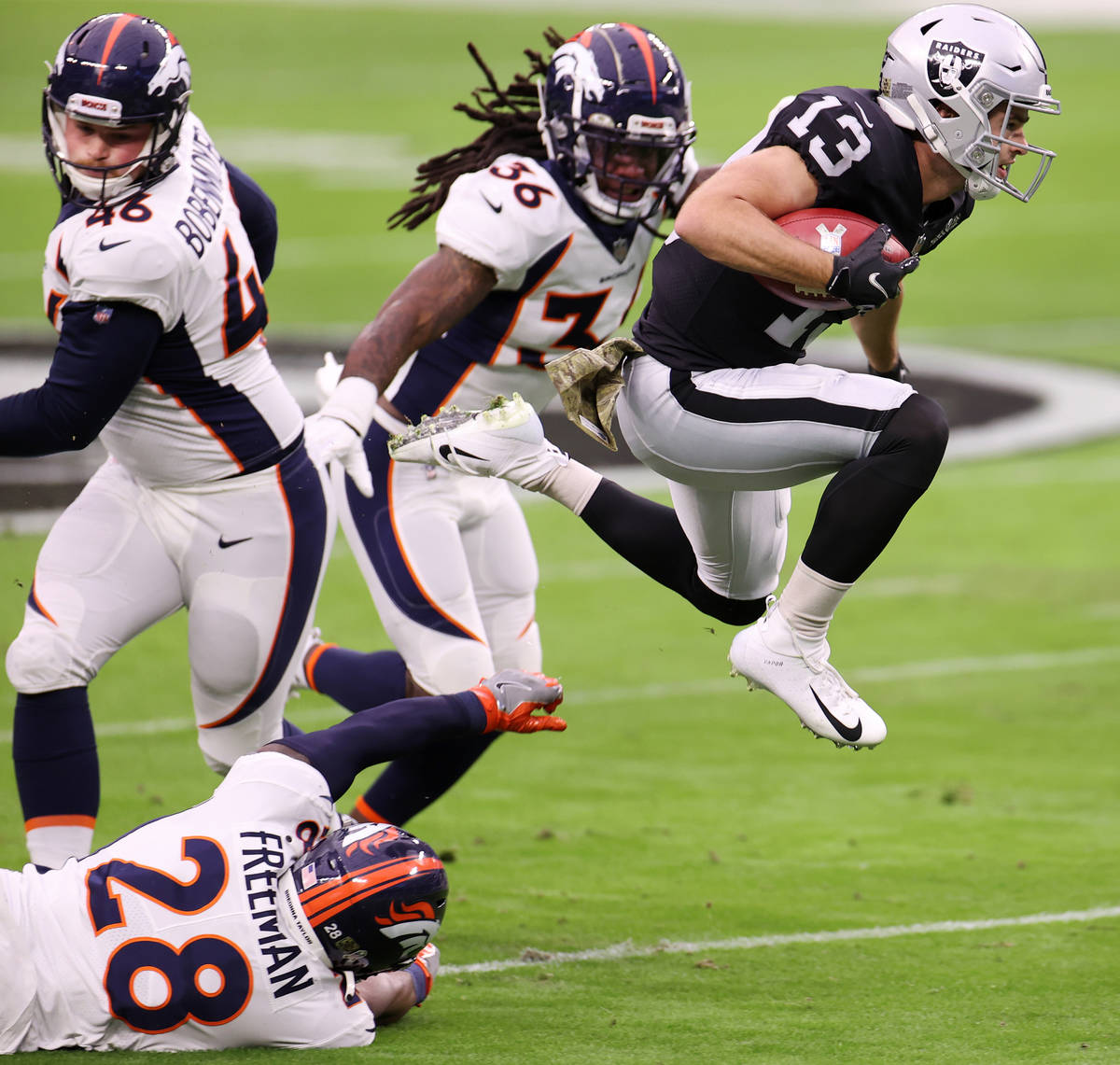 Las Vegas Raiders wide receiver Hunter Renfrow (13) leaps over Denver Broncos running back Royc ...