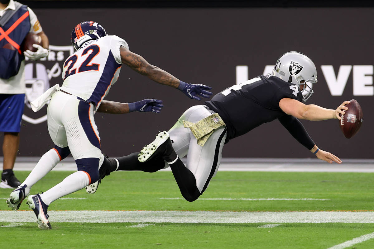 Las Vegas Raiders quarterback Derek Carr (4) leaps for yardage under pressure from Denver Bronc ...