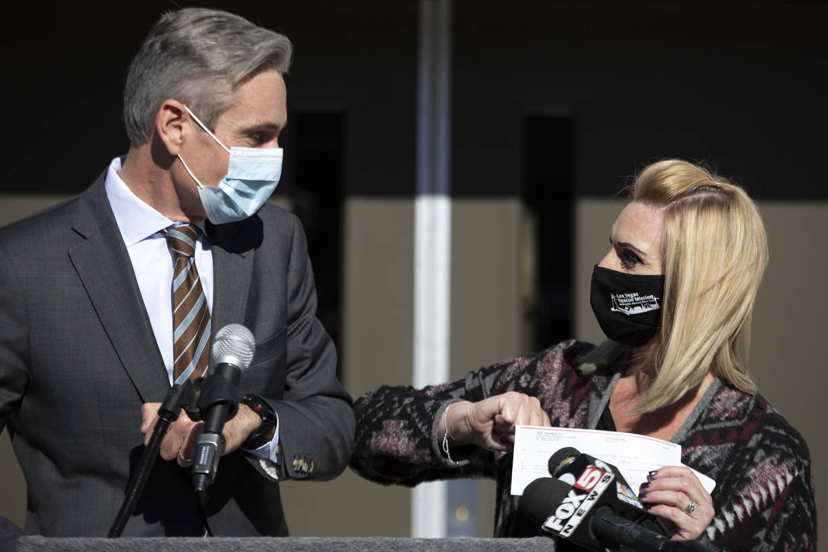 Brian Turmail, vice president of AGC Charities Inc., bumps elbows with Las Vegas Rescue Mission ...