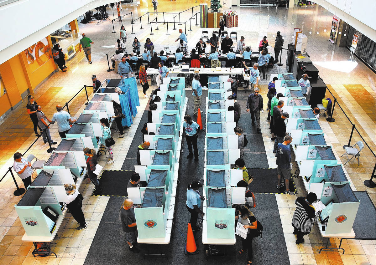 Voters cast their ballots as others sign in at a polling station at Galleria Mall on Tuesday, N ...