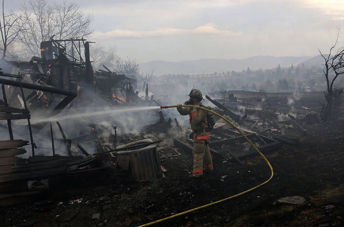 A firefighter tries to put out the final flames of a burned home during the Pinehaven Fire in t ...