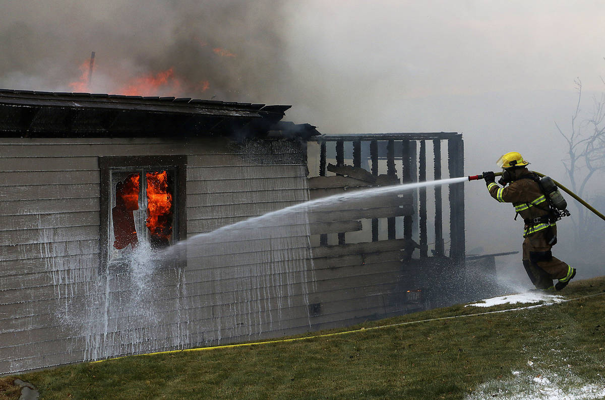 A firefighter tries to save a home during the Pinehaven Fire in the Caughlin Ranch area of Reno ...