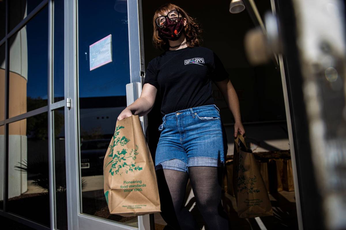 Human resources worker Rachel Clark delivers bags of donated food to vehicles during a food dri ...
