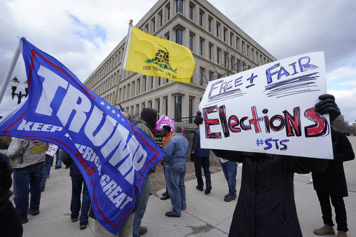 Protesters stand outside the Richard H. Austin state office building during a rally in Lansing, ...