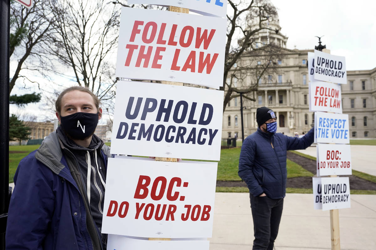 Joscha Weese, left, stands outside the Capitol building during a rally in Lansing, Mich., Satur ...