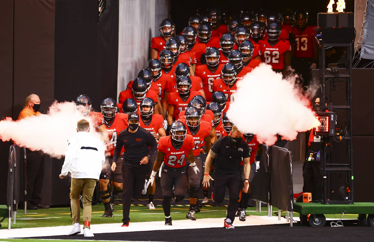 UNLV Rebels players run onto the field before taking on the Wyoming Cowboys in a football game ...