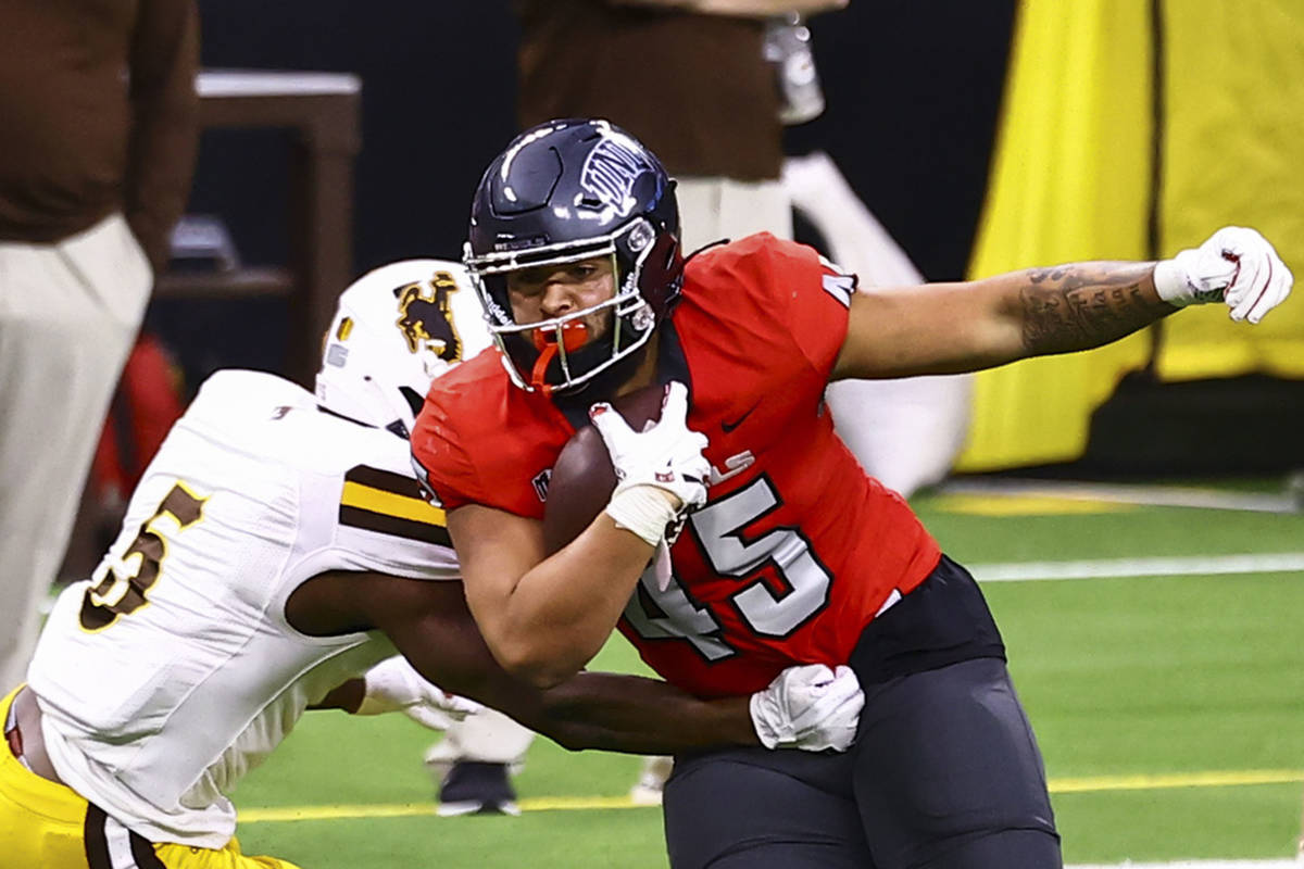 UNLV Rebels tight end Giovanni Fauolo Sr. (45) runs the ball past Wyoming Cowboys safety Esaias ...