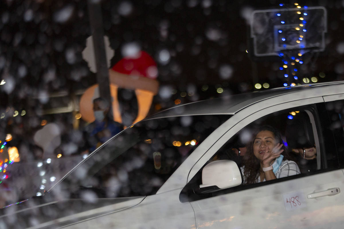 Fake snow sprinkles on passing cars during Hope for the City's drive-through food pantry and ho ...