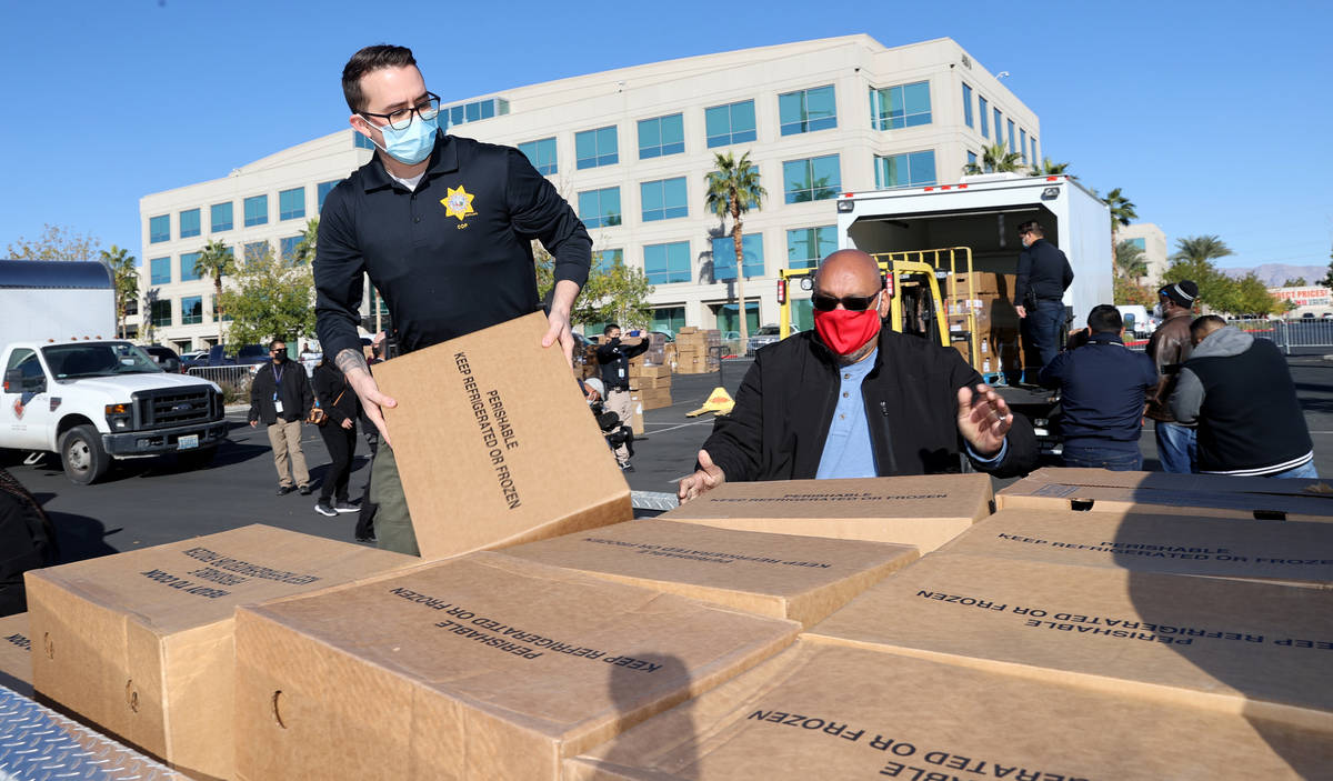 Las Vegas police officer Daniel Russie, left, and volunteer Gene Davila load turkeys at Metropo ...