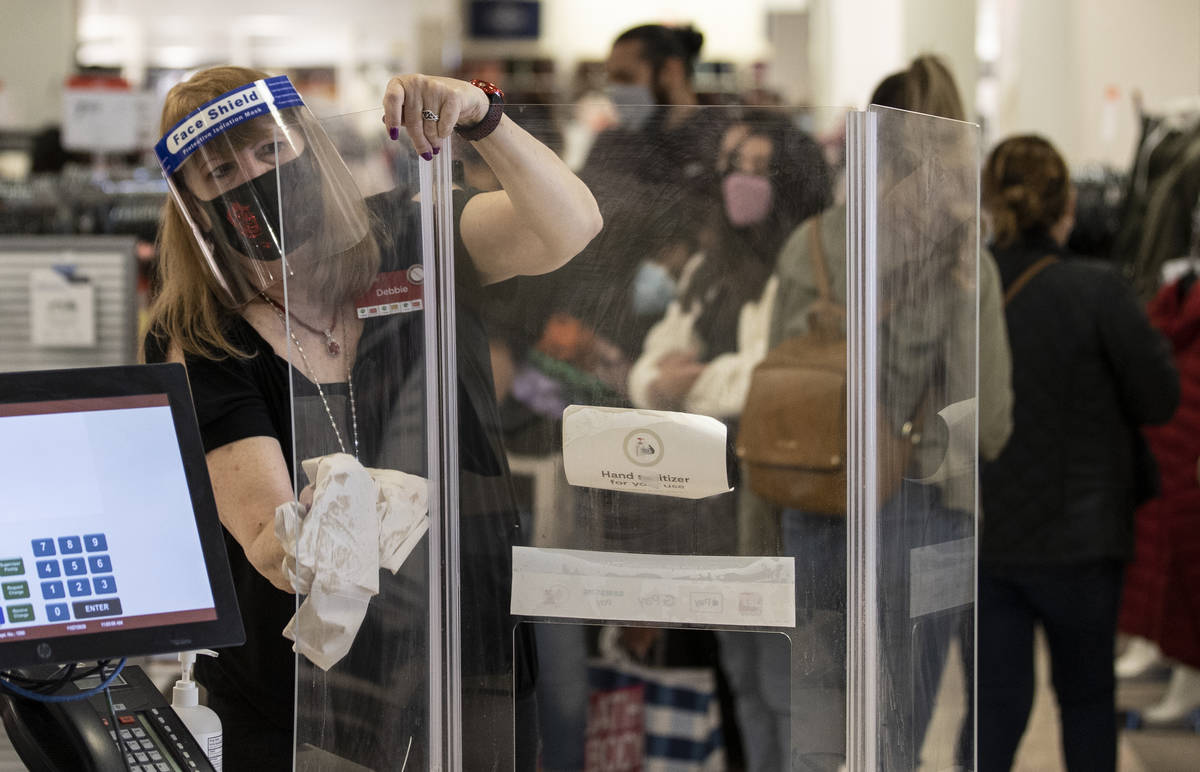 J.C. Penney cashier Debbie Steinberg, left, sanitizes the checkout area during Black Friday at ...