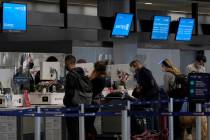 Travelers wearing masks check in at United desks at San Francisco International Airport during ...